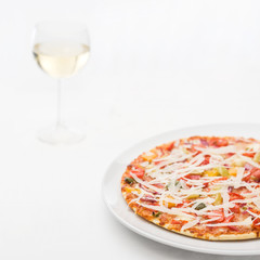 Pizza mit Weißwein auf weissem Porzellan und weisser Tischdecke