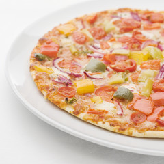 Gemüsepizza auf weissem Teller auf weisser Tischdecke