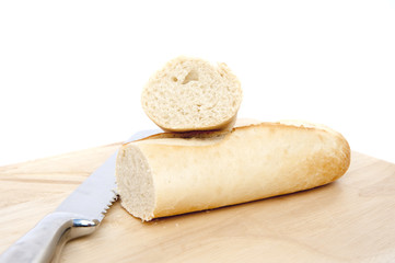 Baguette and bread knife on chopping board isolated on white