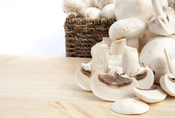 Fresh champignon mushrooms in rustic basket isolated on white