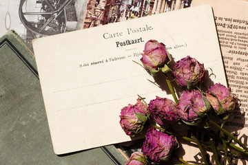 antike Postkarte und getrocknete Rosen