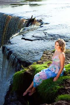 beautiful girl on brink of precipice of river waterfalls