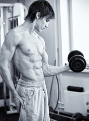 Fototapeta na wymiar Powerful muscular man lifting weights in gym
