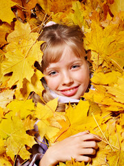 Kid in autumn orange leaves.