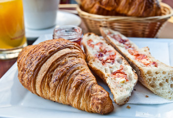 Breakfast with coffee and croissants in a basket on table