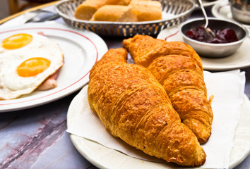 Breakfast with coffee and croissants in a basket on table