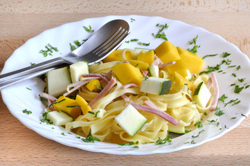 włoskie tagliatelle z warzywami i szynką na drewnianej desce