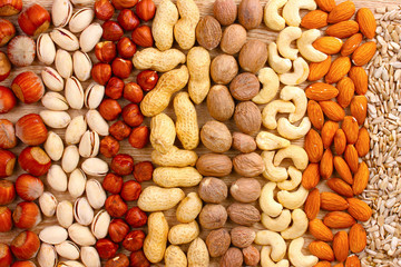 nutmeg, peanuts, hazelnuts and almonds on wooden background