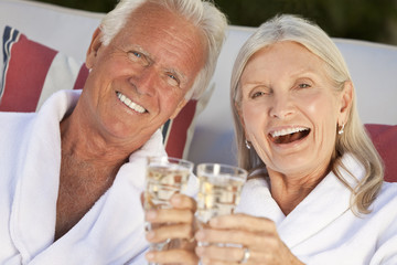 Happy Senior Couple In Spa Bathrobes Drinking Champagne