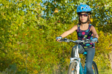 Happy girl cycling outdoors. Smiling child on bicycle