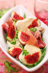Fresh salad with figs, prosciutto and goat cheese, soft focus
