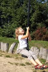 Fun in the park. Girl pulls down the hill on a rope - obrazy, fototapety, plakaty
