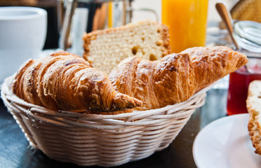 Breakfast with coffee and croissants in a basket on table
