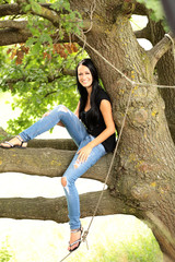 Junge Frau sitzt im Baum