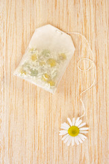 Bag of chamomile tea over wooden background - concept