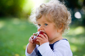 little girl is eating a apple