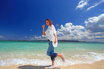 波打ち際を歩く笑顔の女性