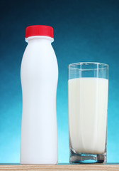 Tasty milk in glass and bottle on blue background