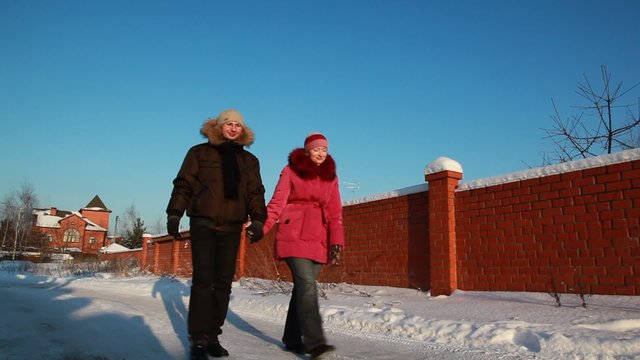 Woman and man walking outdoors at winter, house