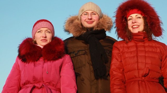 Man and two women in jacket talking outdoors at winter