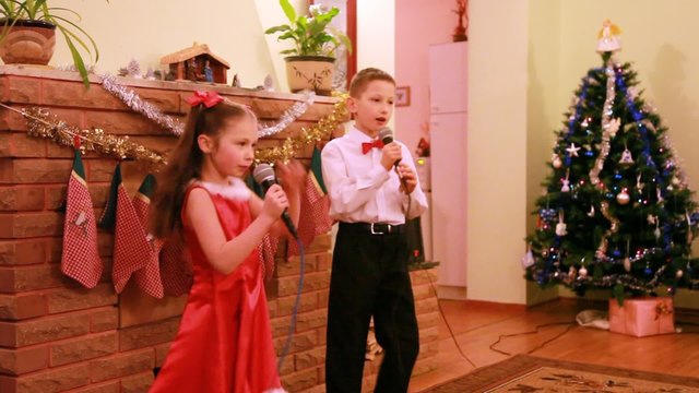Brother and sister sing song into microphone