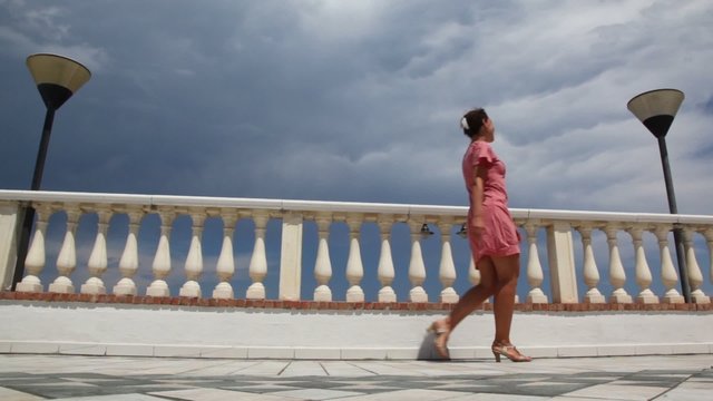 Woman goes from left to right along the balustrade