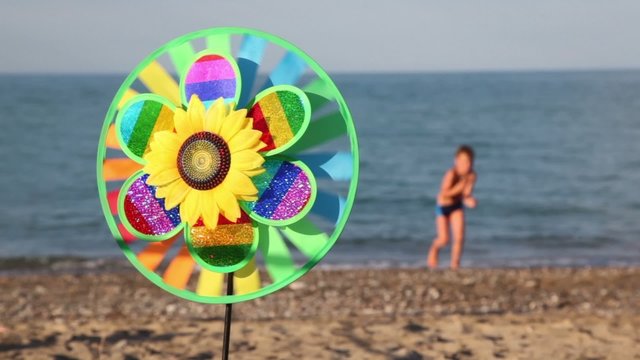 Toy spins on background of sea and boy walking on shore