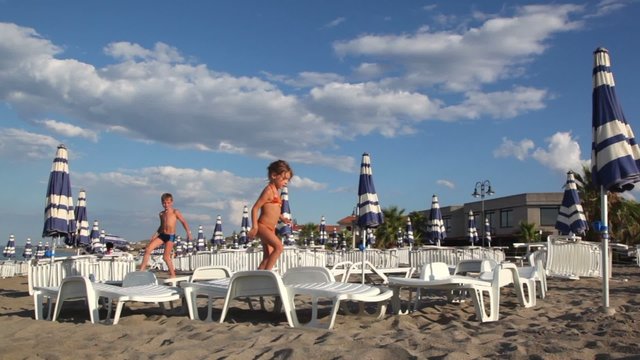 Children jumping on deckchairs, then comes third child