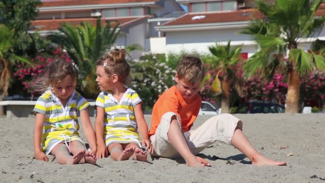 Tree kids sitting on sand