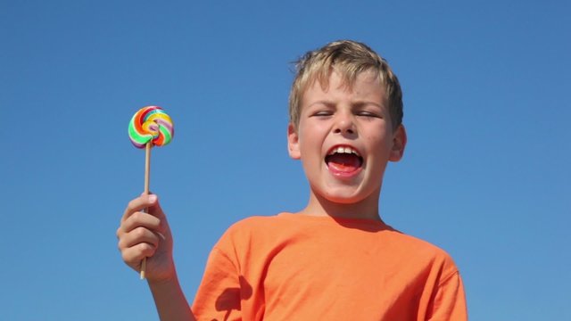The boy holding a candy, and says the phrase