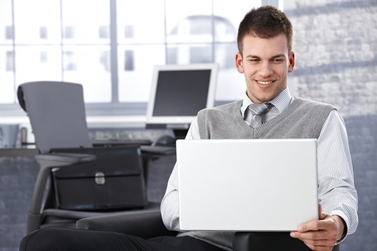 Young businessman browsing internet smiling