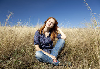 Naklejka na ściany i meble Portrait of happy red-haired girl on autumn grass.