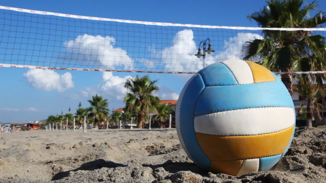 Ball lies on sand under volleyball net at beach