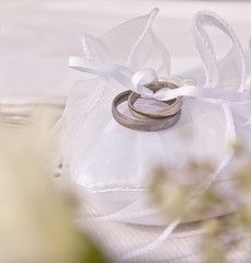 two engagement rings bow on a heart-shaped pillow