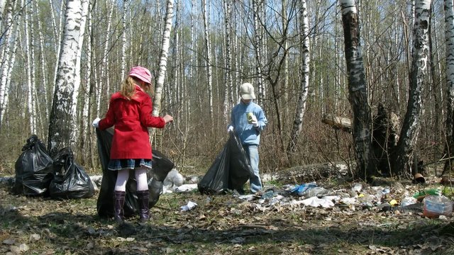 Children and father collect trash to garbage bags in forest