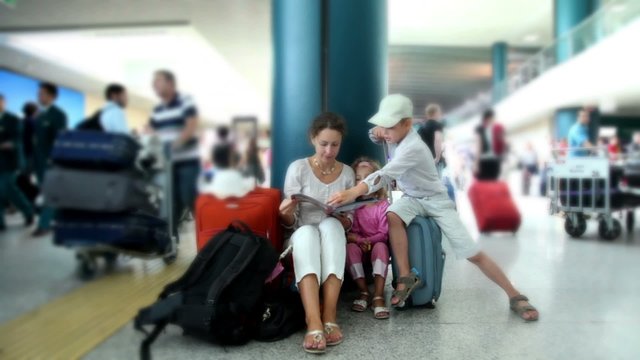 Mother and kids sit in airport and reading book