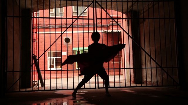 woman performs modern dance with cloth near lattice gate