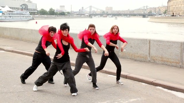 Four girls active dance synchronously on quay