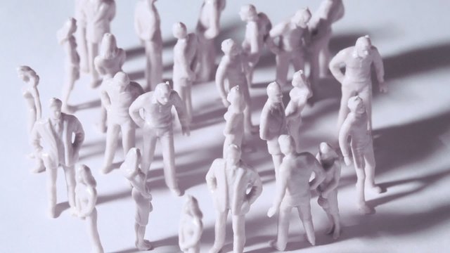 Group of little unpainted toy men and women stand