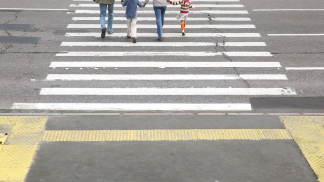 Parents and kids cross road by pedestrian crossing