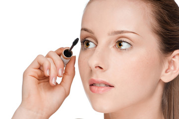 Beautiful woman applying mascara on her eyelashes