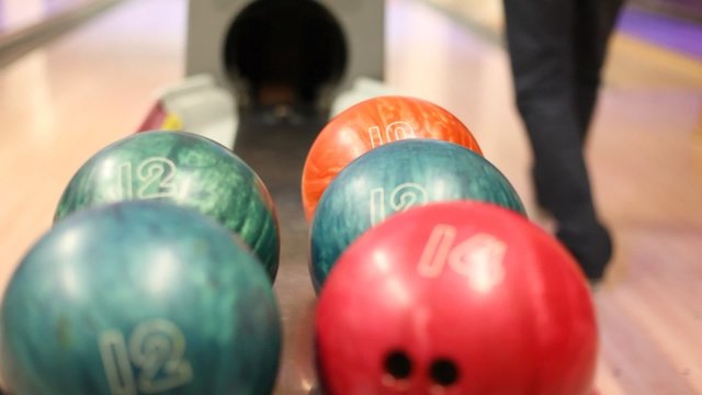 Close-up of bowling balls, man takes ball