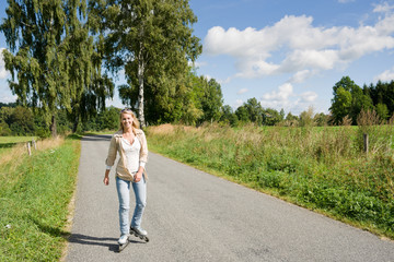 Inline skating young woman on sunny asphalt road