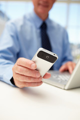 Senior businessman with laptop and phone