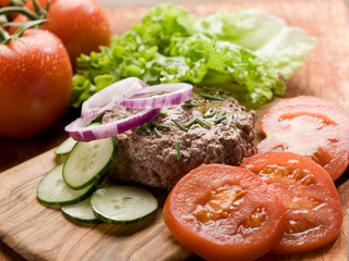 hamburger with slice vegetables over cutting board