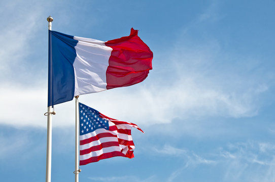 Photo de deux drapeaux français et des Etats Unis d'Amérique (US) flottant sur dons de ciel bleu, symbole de l'amitié et la coopération franco américaine, France et USA