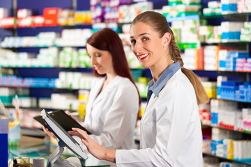 Pharmacist with assistant in pharmacy