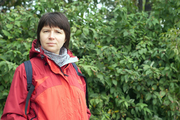 Portrait of woman dressed in red blazer with backpack on nature