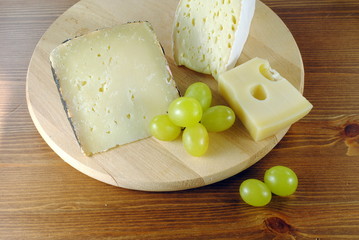 Italian cheese with grapes on wooden cutting board
