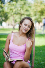 girl in a pink vest sits in a chaise lounge and reads the book